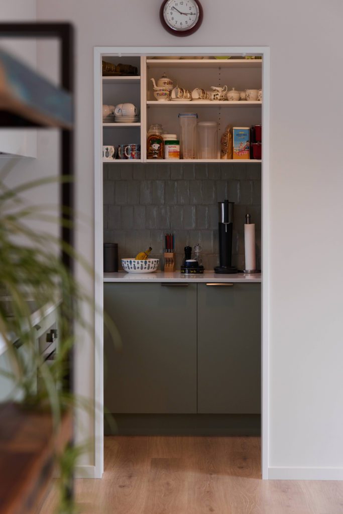 Kitchen pantry featuring green cabinetry and green tiles. Designed and Built by R&B Build